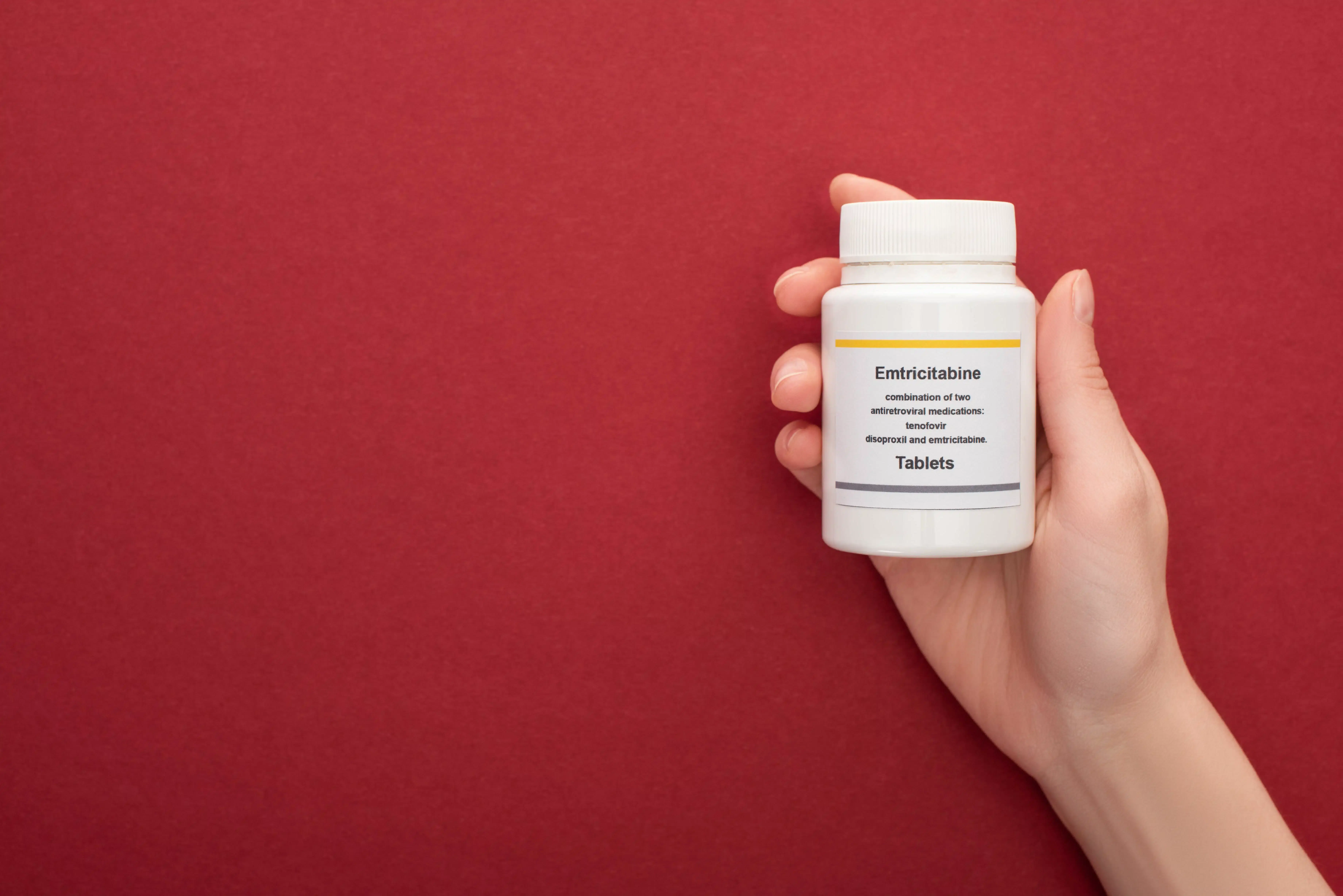 A Container with Emtricitabine Tablets on a Red Background